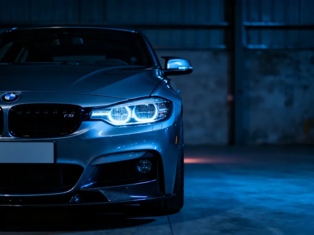 BMW F30 zaparkowane w garażu, wyeksponowany przedni zderzak i reflektory w chłodnym, kinowym oświetleniu.